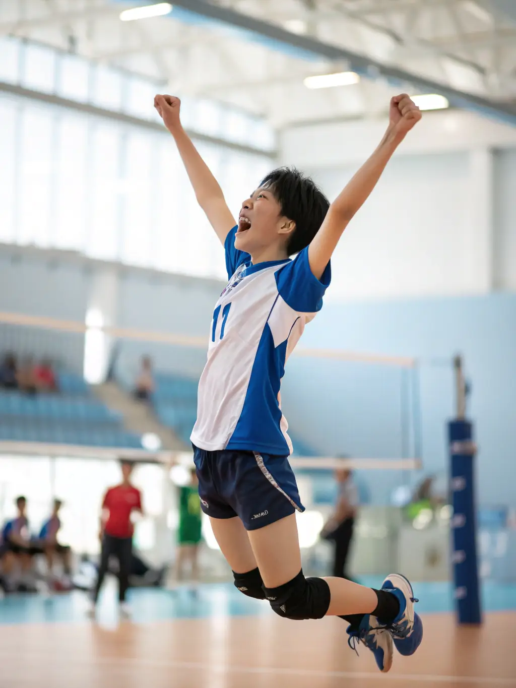 A student smiling confidently after scoring a point during an inter-faculty volleyball tournament, highlighting the sense of achievement and personal growth.